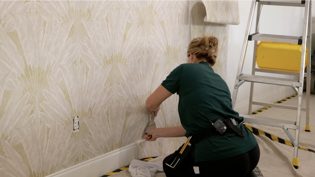 Wallpaper installer carefully smoothing a patterned wallcovering